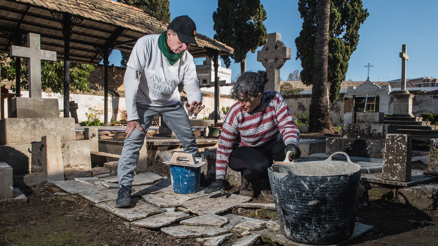 Francisco Ortiz y Diana, una de las voluntarias, realizando tareas de restauración en una de las tumbas vandalizadas del cementerio.