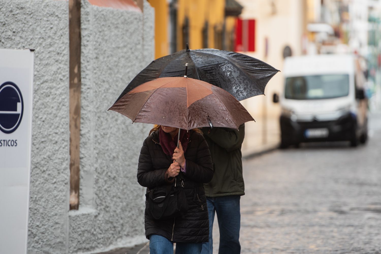 Dos personas se refugian de la lluvia bajo sus paraguas en Andalucía.
