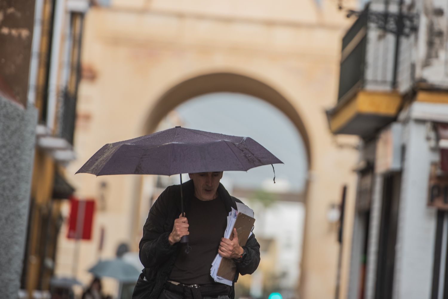 Una persona se refugia de la lluvia en Sevilla.