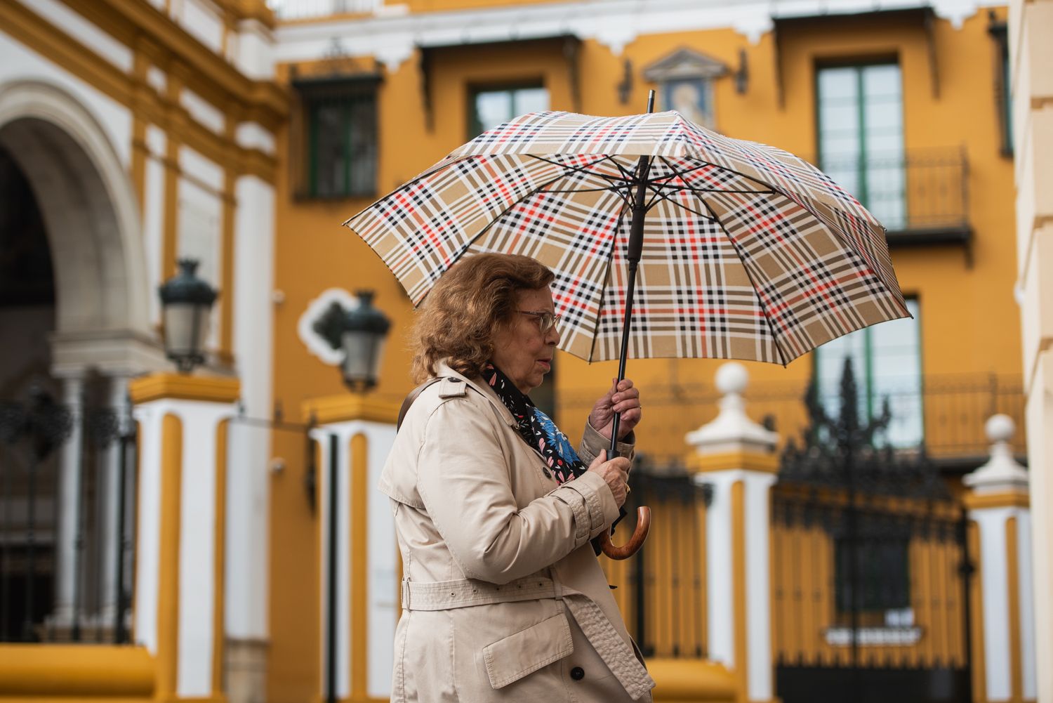 Una mujer, resguardándose de la lluvia en Sevilla.