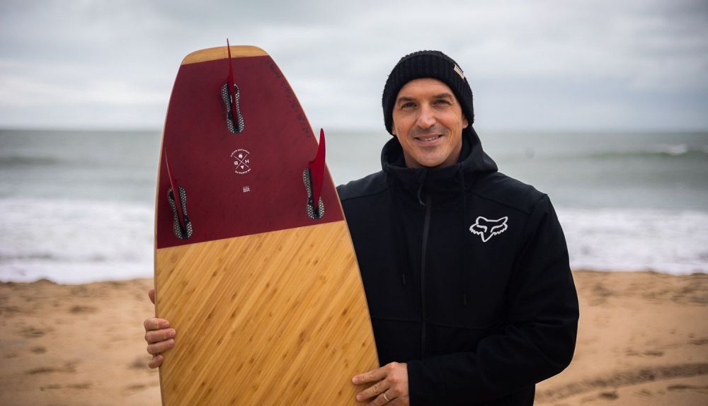 Chema posa con una de las tablas que vende en la playa de Las Redes.