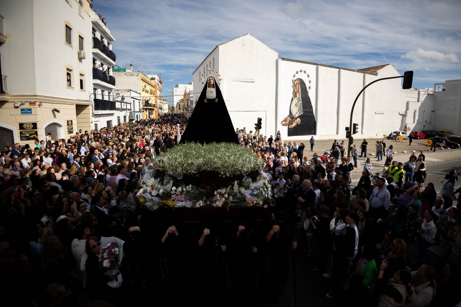 La Virgen de Amor y Sacrificio en las andas y, al fondo, el mural de Pol Tattoo.