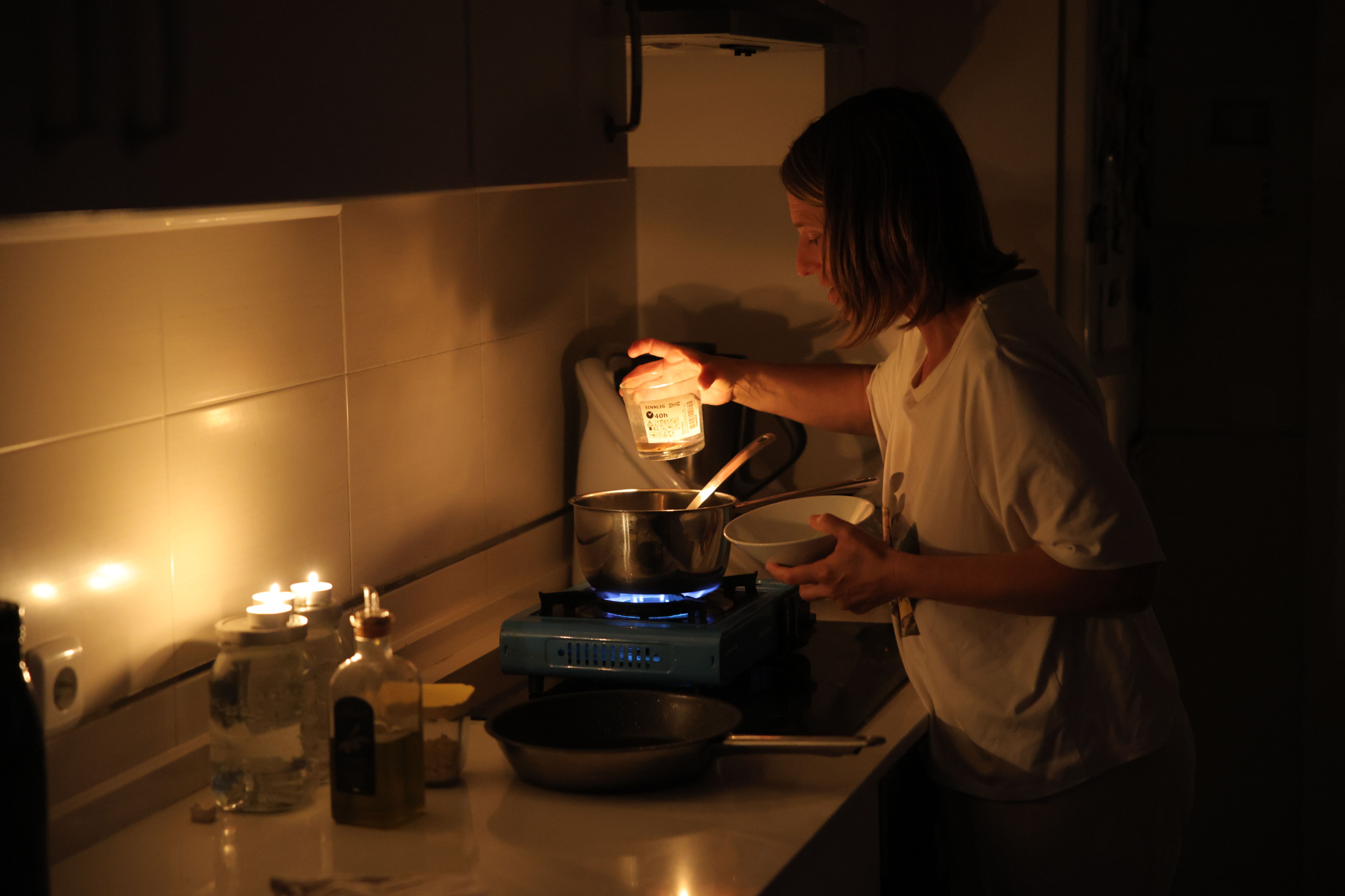 Una mujer, cocinando con velas durante el gran apagón.