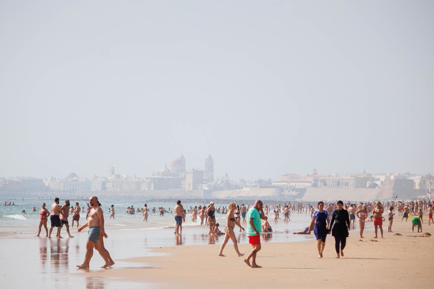 Varias personas pasean por una playa durante una ola de calor en Cádiz, en una imagen de archivo.