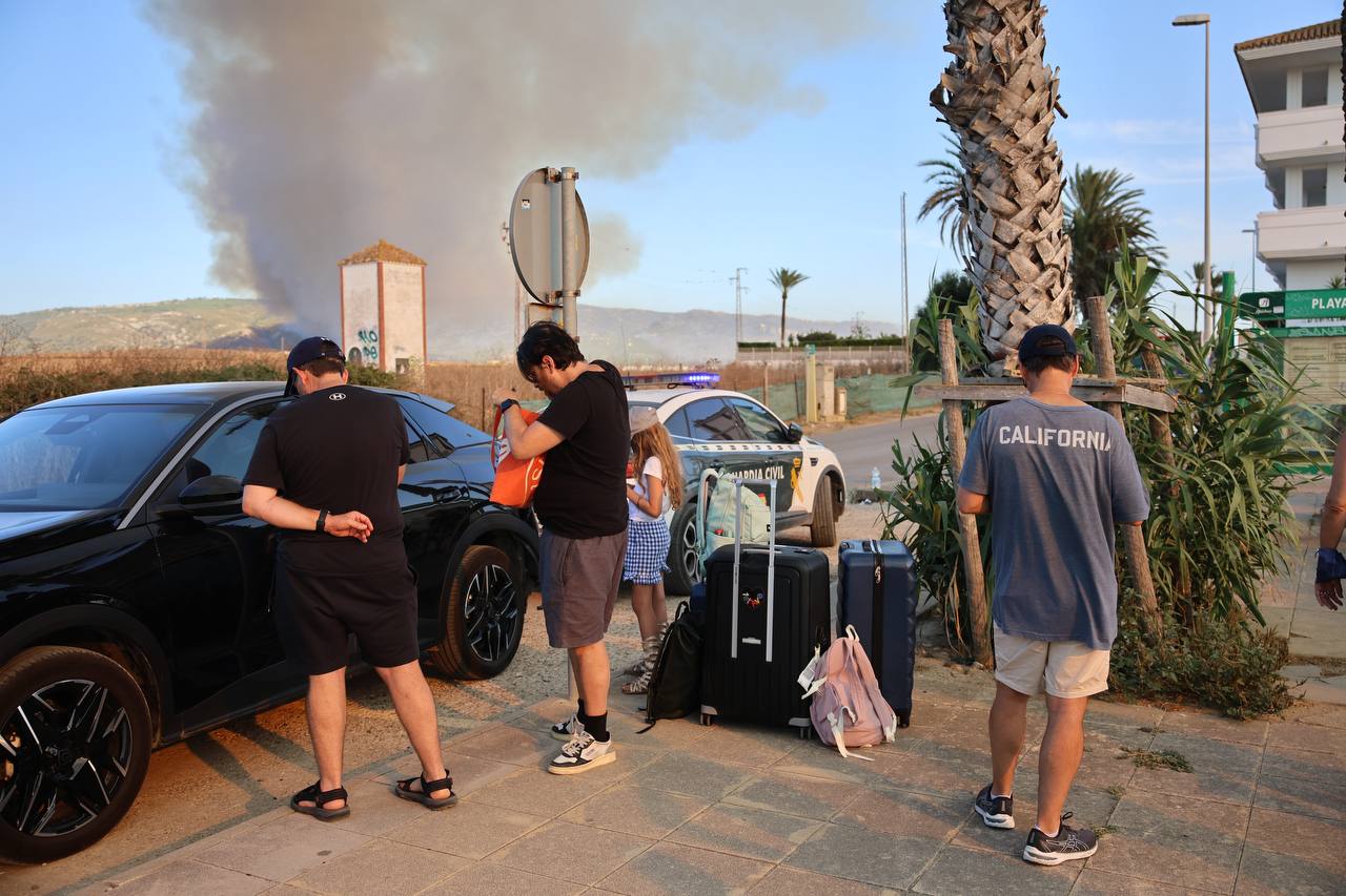 Varias personas en Zahara, con el incendio al fondo.