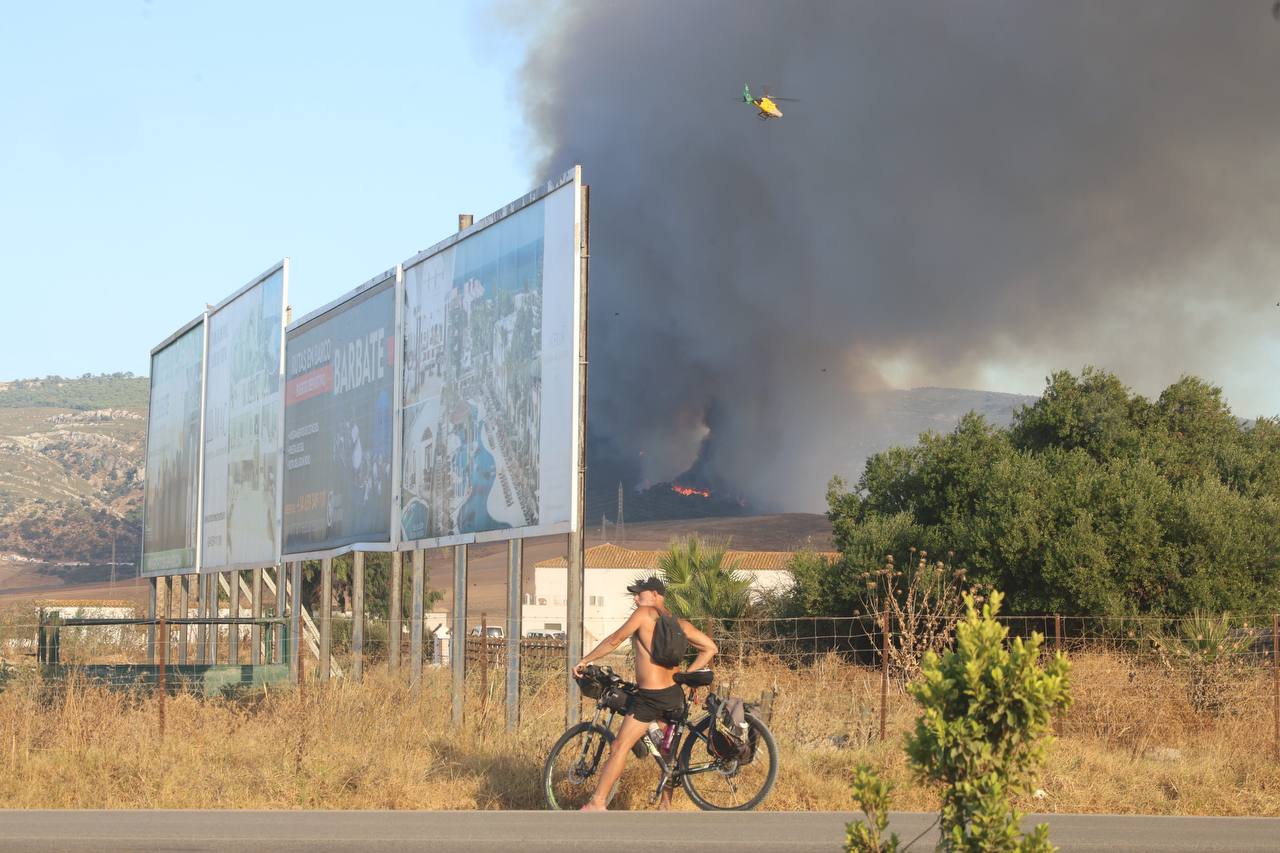 Un chico en bicicleta en Zahara, mientras Infoca sofoca a lo lejos el incendio.