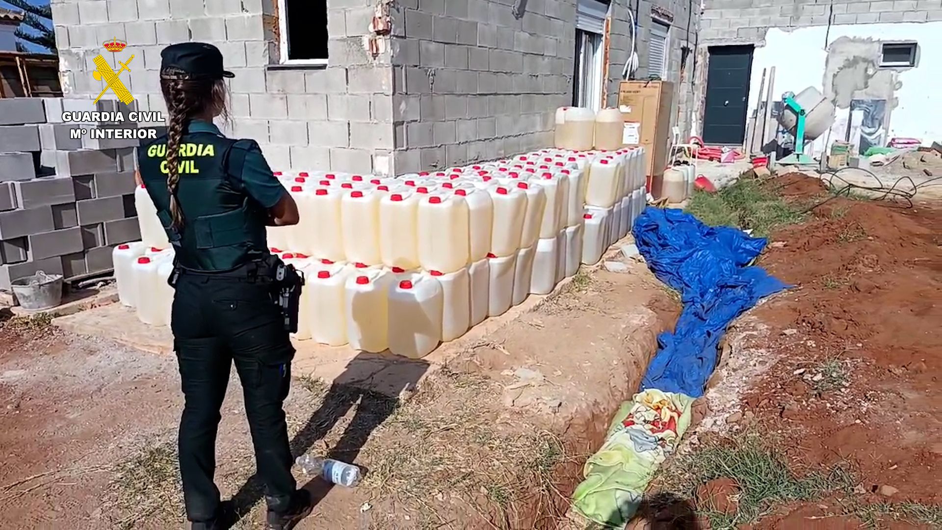 Una agente, delante de petacas de gasolina encontradas en la vivienda de Chiclana.