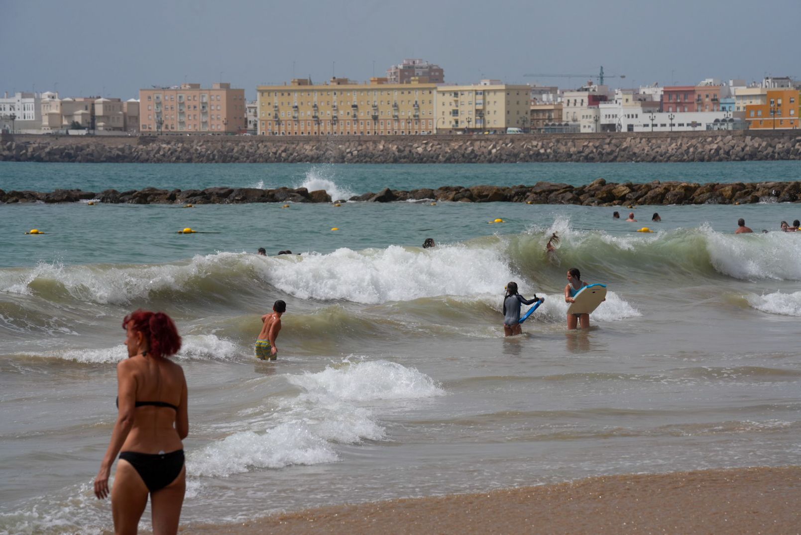 Bañistas en la playa de Santa María del Mar de Cádiz, este verano, con mar de fondo.