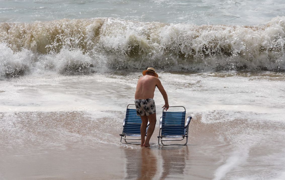 Una persona, a punto de perder las sillas en la orilla de Santa María del Mar, en Cádiz.