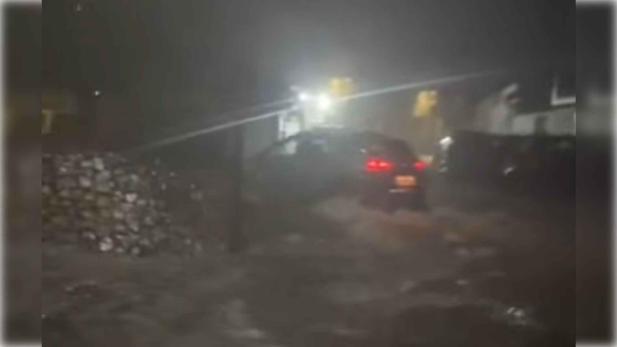 Un coche circula con dificultades por el agua en una rotonda de Puebla de Guzmán.