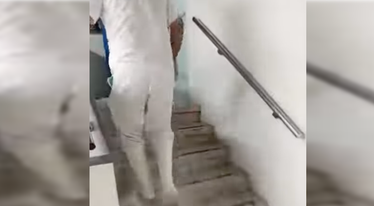 Un sanitario sube por las escaleras del Hospital Macarena, por donde caen agua en cascada.