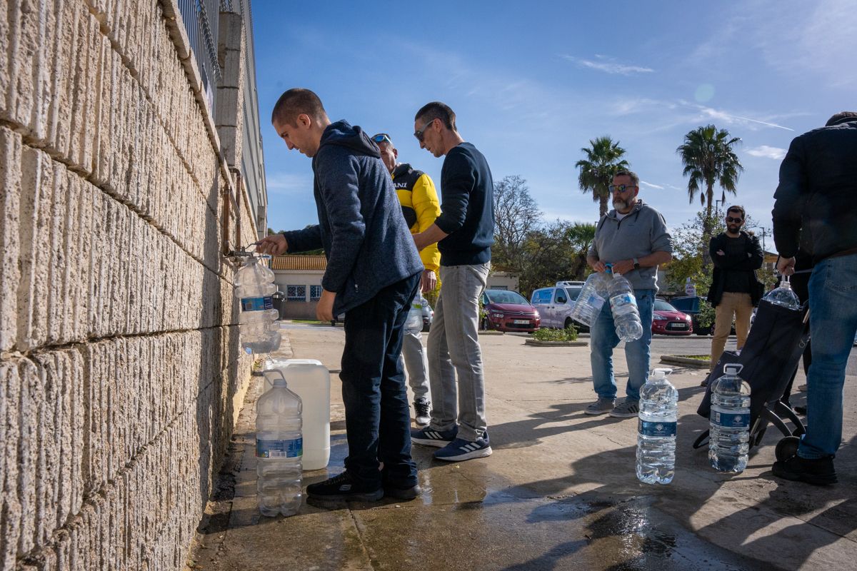 Vecinos de barriadas afectadas de Puerto Real hacen cola para llevar agua potable a sus casas.