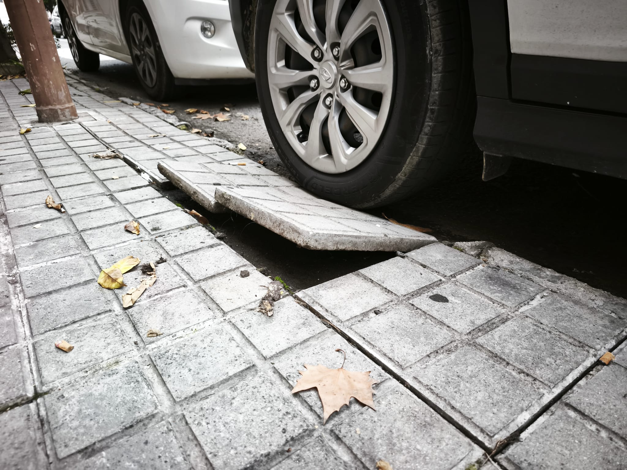 Una acera levantada tras aparcar un coche.
