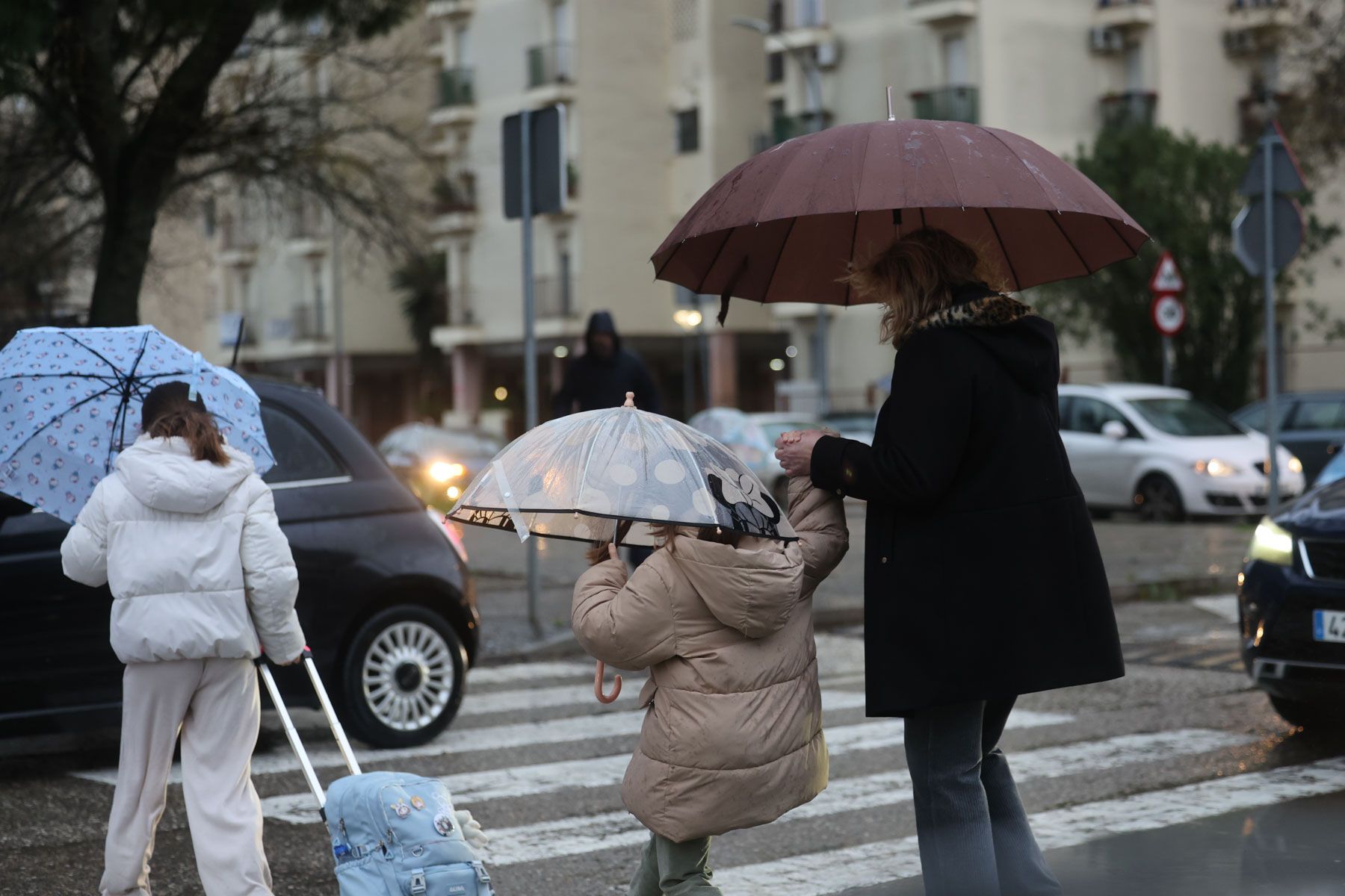 Familias con niños camino a las clases en un colegio de Jerez, este jueves de temporal.