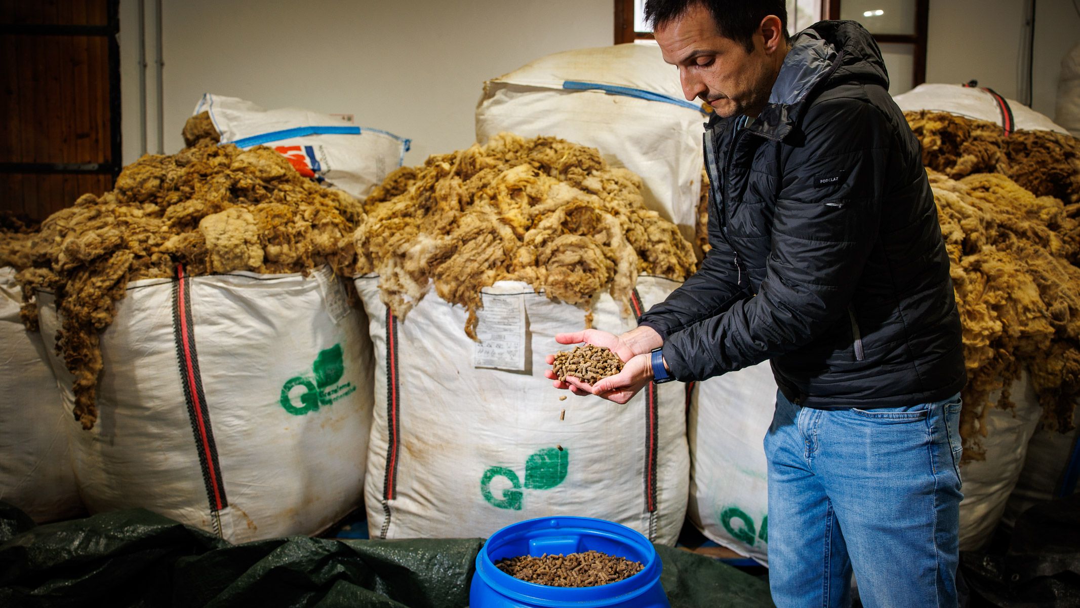 El ingeniero industrial Juan Baena enseña los pellets fertilizantes que se fabrican en Grazalema, con los sacos de lana al fondo.