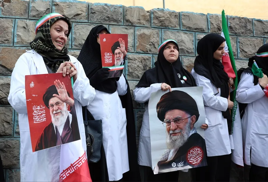 Personal médico iraní sostiene carteles del difunto líder supremo iraní, el ayatolá Alí Jamenei.