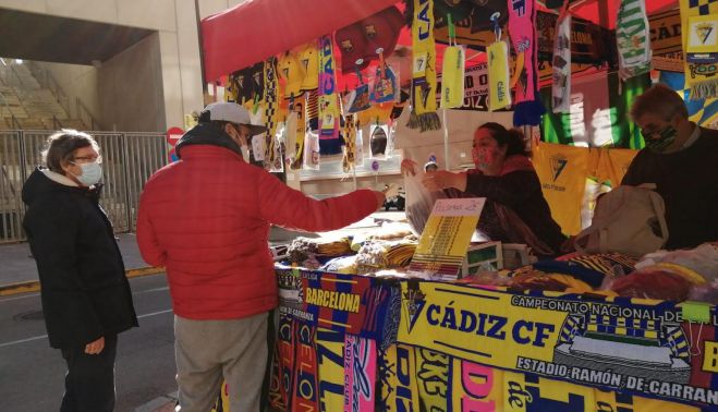 Unos aficionados compran bufandas.