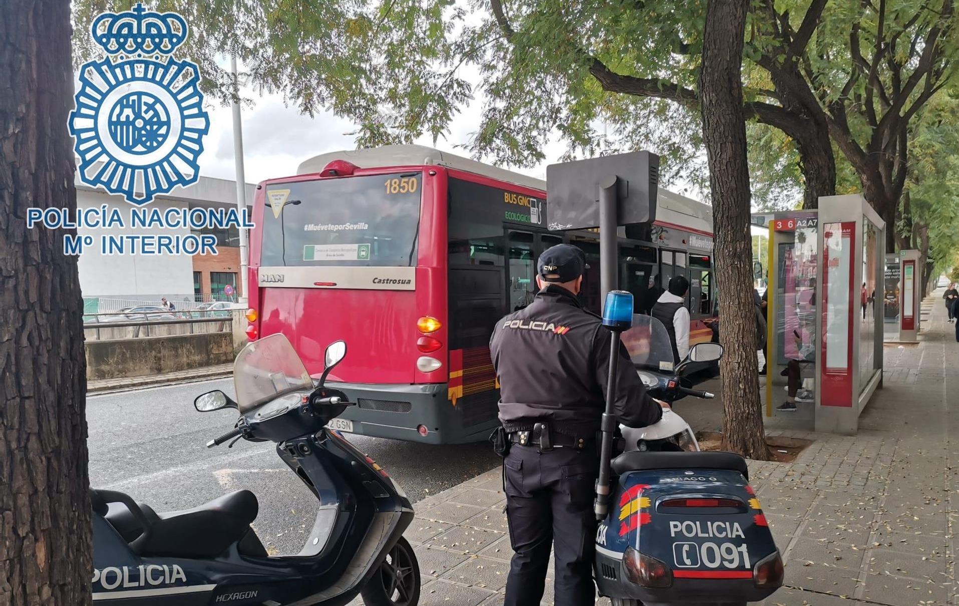 Un agente de Policía Nacional, junto a un autobús de Tussam en Sevilla.