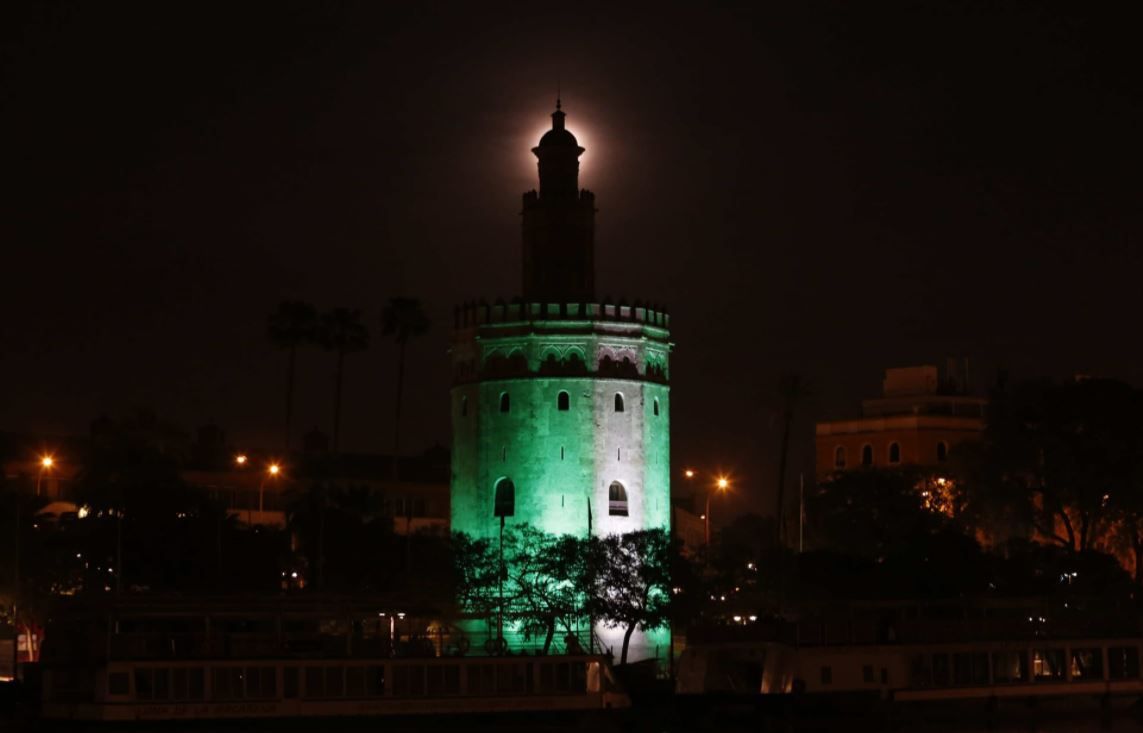 La Torre del Oro iluminada con luces con la bandera de Andalucía, uno de los monumentos más significativos de Sevilla..