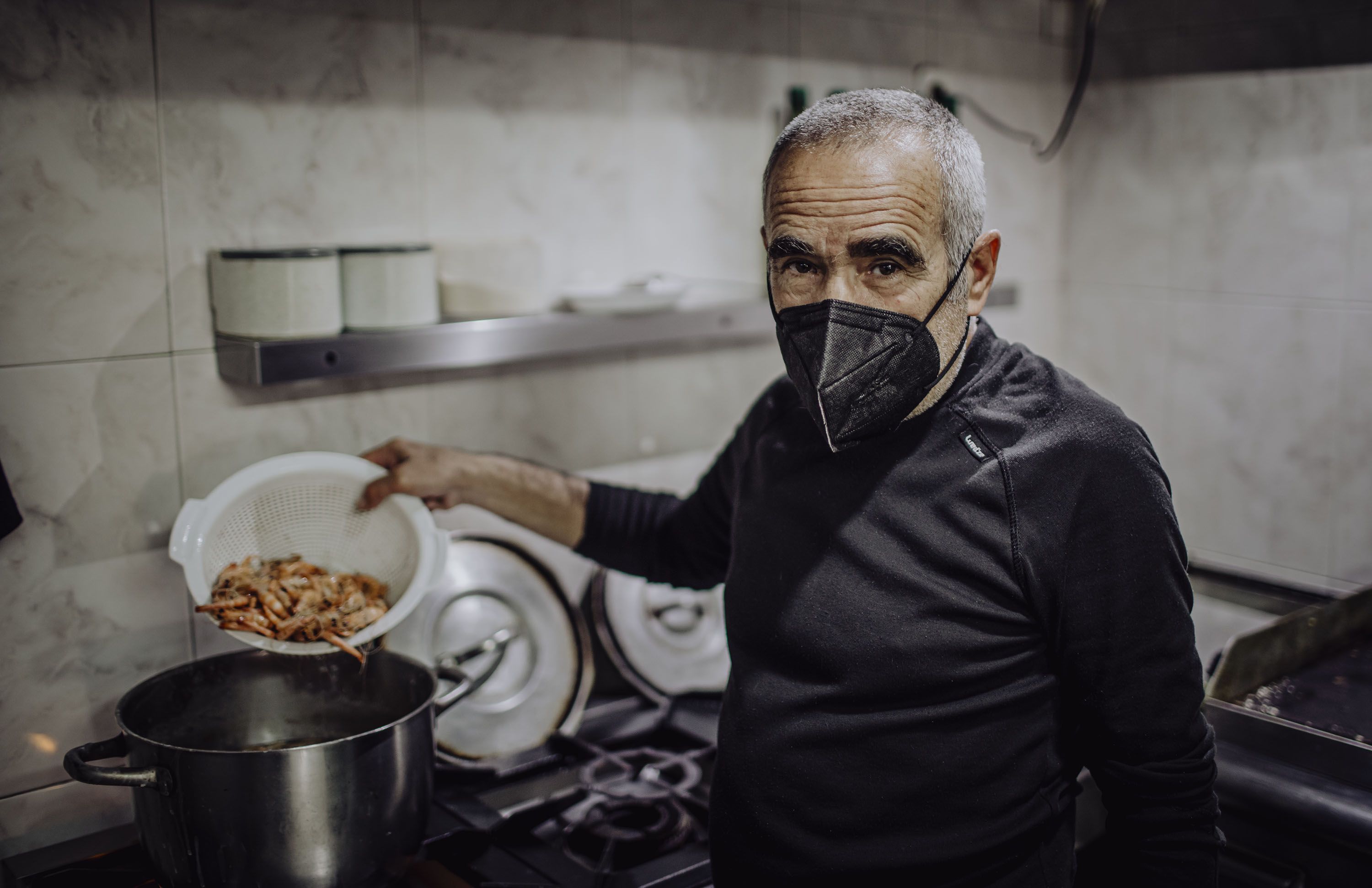 Juan Osorio cociendo unas gambas en la cocina.