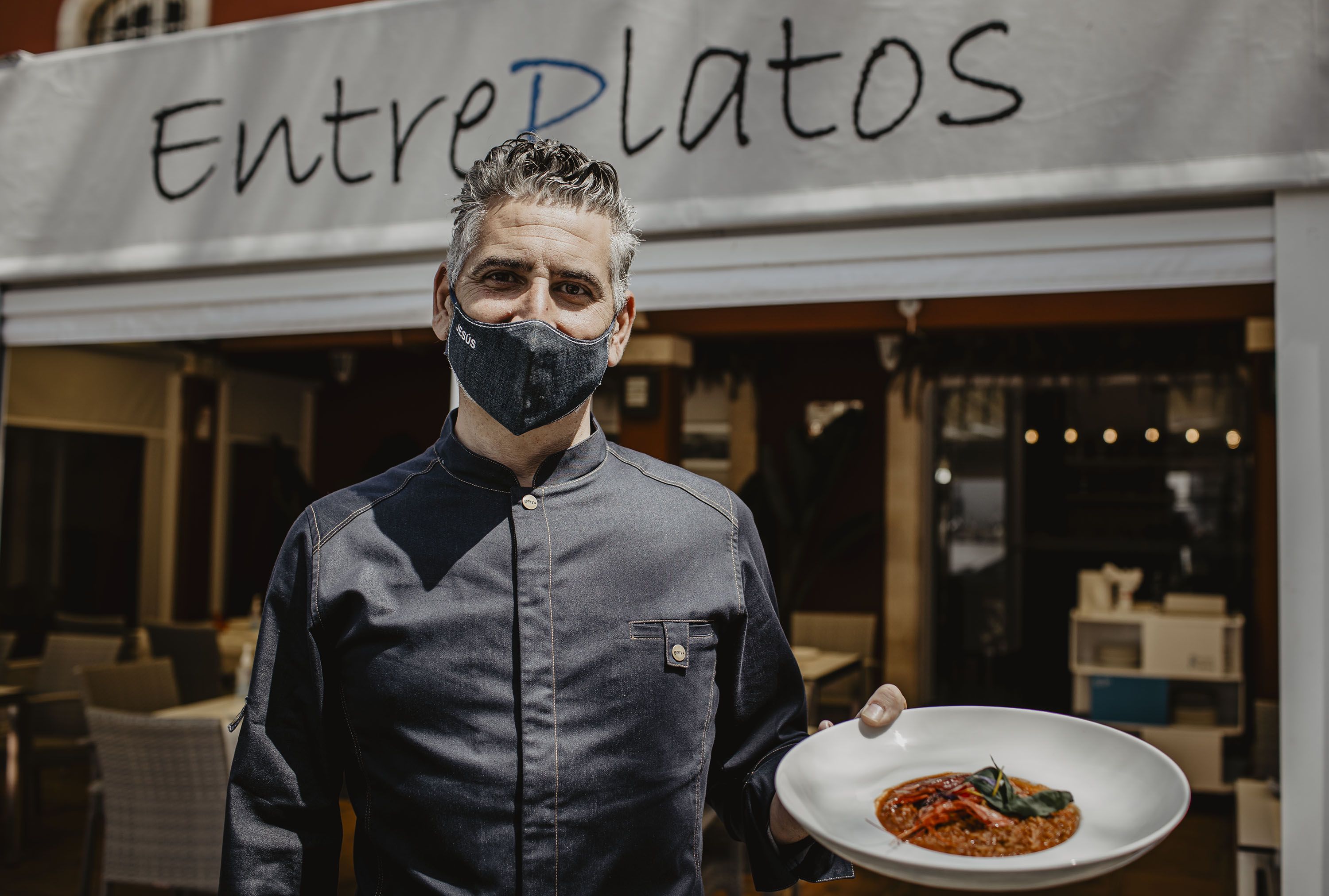 Jesús Matilla en la puerta del restaurante Entreplatos con un plato de arroz con carabineros.
