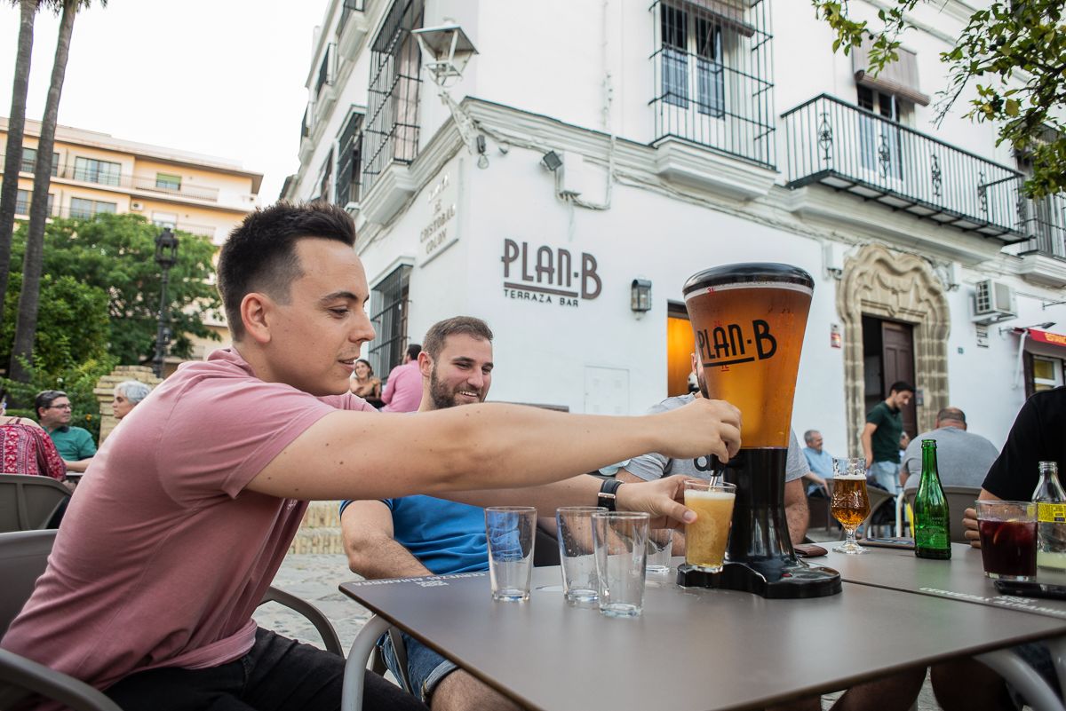 Varias personas beben cerveza de la torre en la terraza de Plan B.