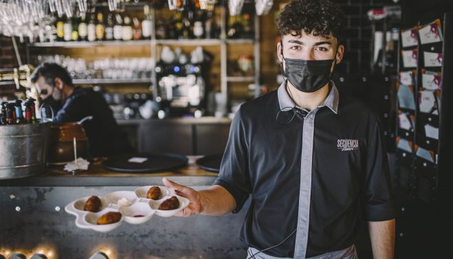 4. Un camarero de Secuencia 9 con una tapa de croquetas