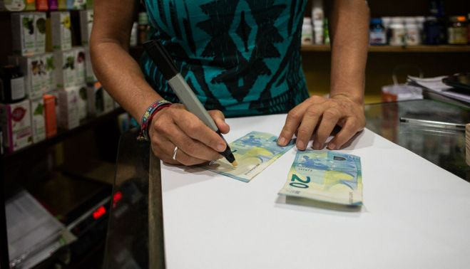 La necesidad de comprobar la autenticidad de los billetes aumenta en las tiendas del centro.   MANU GARCÍA.