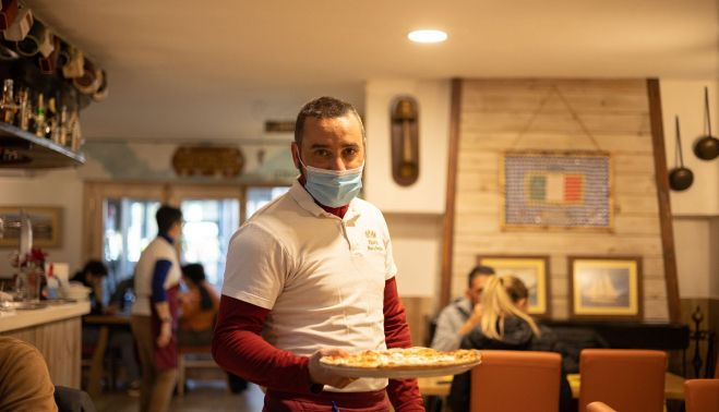 Samuel con una pizza en el interior del local.