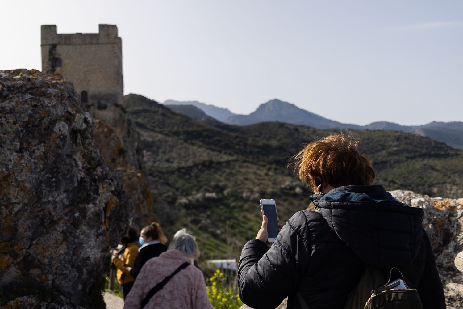 Una mujer camina por la villa medieval de Zahara de la Sierra, con la torre del Homenaje del castillo al fondo Una mujer camina por la villa medieval de Zahara de la Sierra, con la torre del Homenaje del castillo al fondo